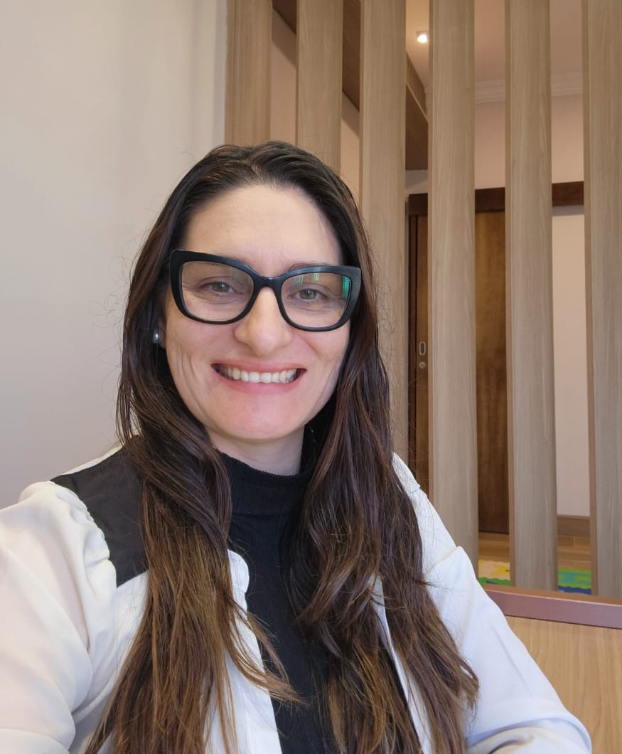 Renata Allan, psicopedagoga clínica sorrindo em ambiente acolhedor
